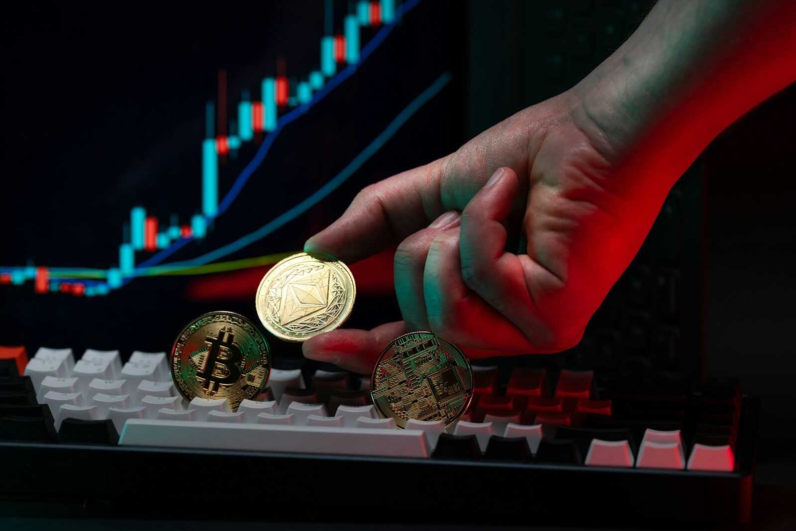 A person holding a coin in front of a computer keyboard